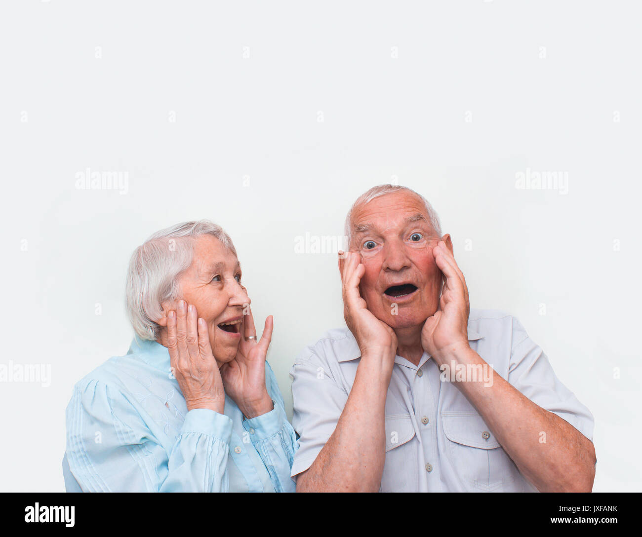 La coppia di anziani sorpreso sollevando entrambe le mani Foto Stock