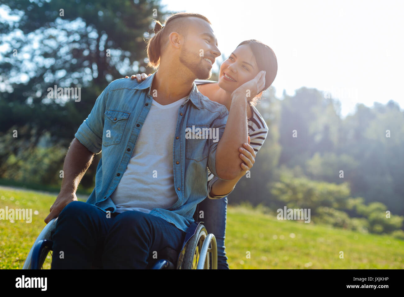 Uomo sorridente con disabilità carezzevole delle sue mogli guancia Foto Stock