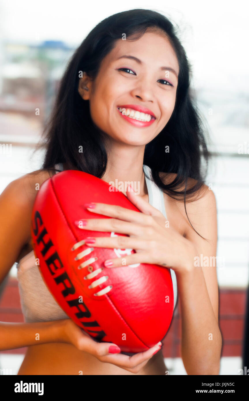 Giovane donna asiatica azienda Australiana AFL Football Foto Stock