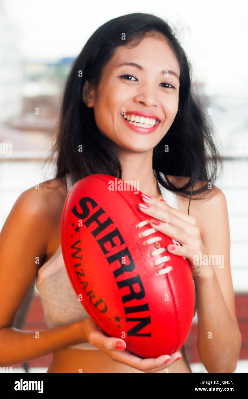 Giovane donna asiatica azienda Australiana AFL Football Foto Stock