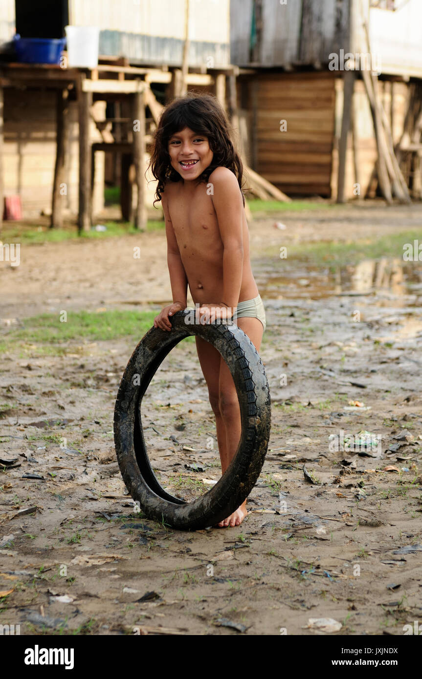 Il Perù, Amazzonia - 23 giugno: Giovani Native American giocando con il pneumatico nel suo villaggio nella giungla amazzonica nel giugno 23, 2012 Foto Stock