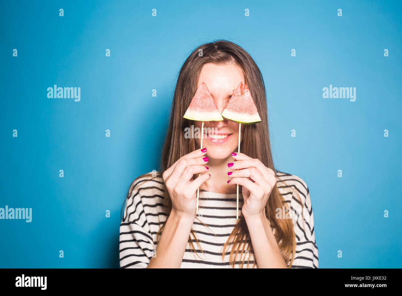 Estate, vacanze, dieta e vegani concetto - Bella sorridente giovane donna holding anguria fetta su stick Foto Stock