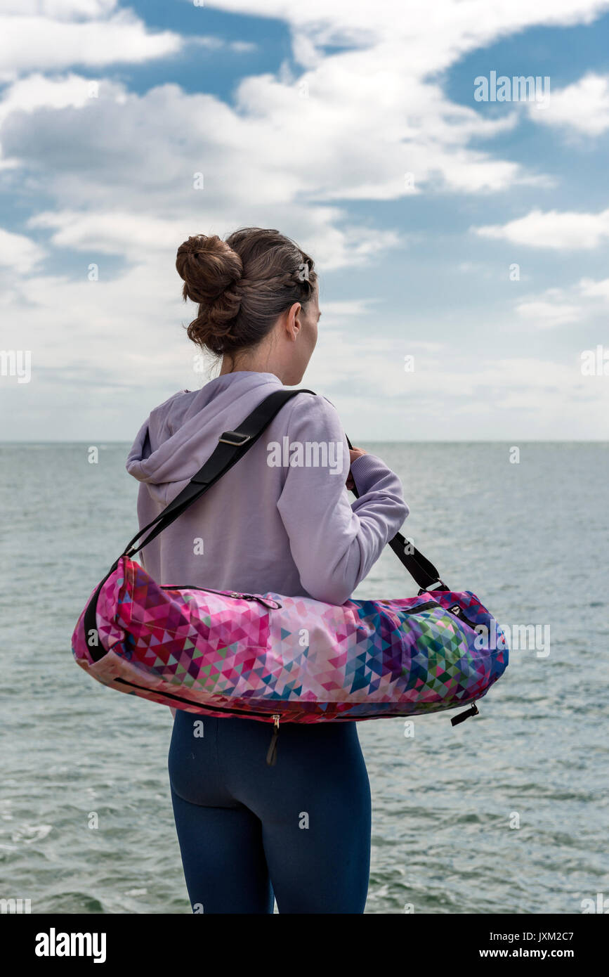 La donna che porta un materassino yoga in un sacchetto di mat Foto Stock