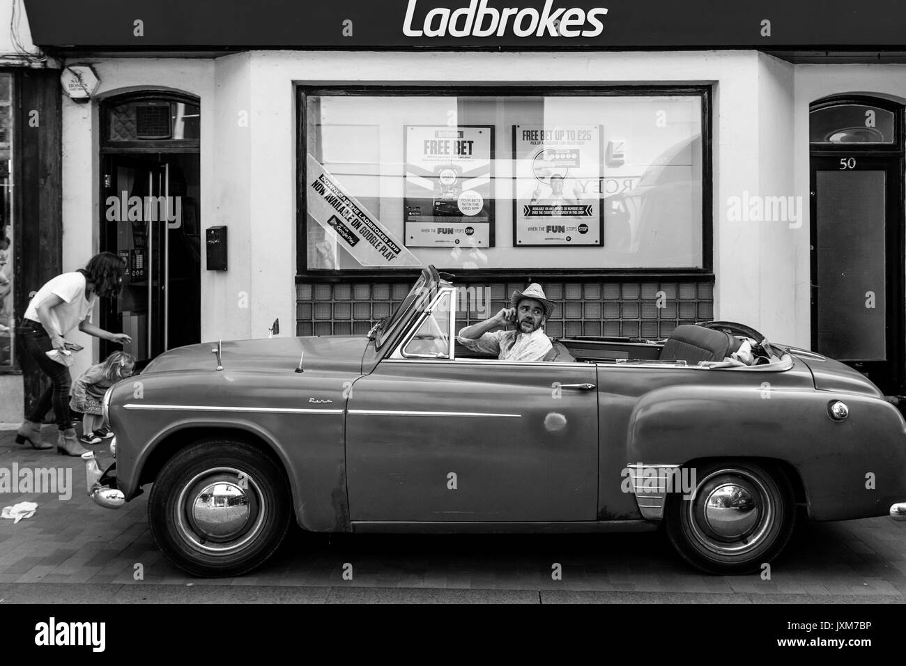 Uomo seduto in un auto a parlare su un telefono mobile, High Street, Lewes, Sussex, Regno Unito Foto Stock