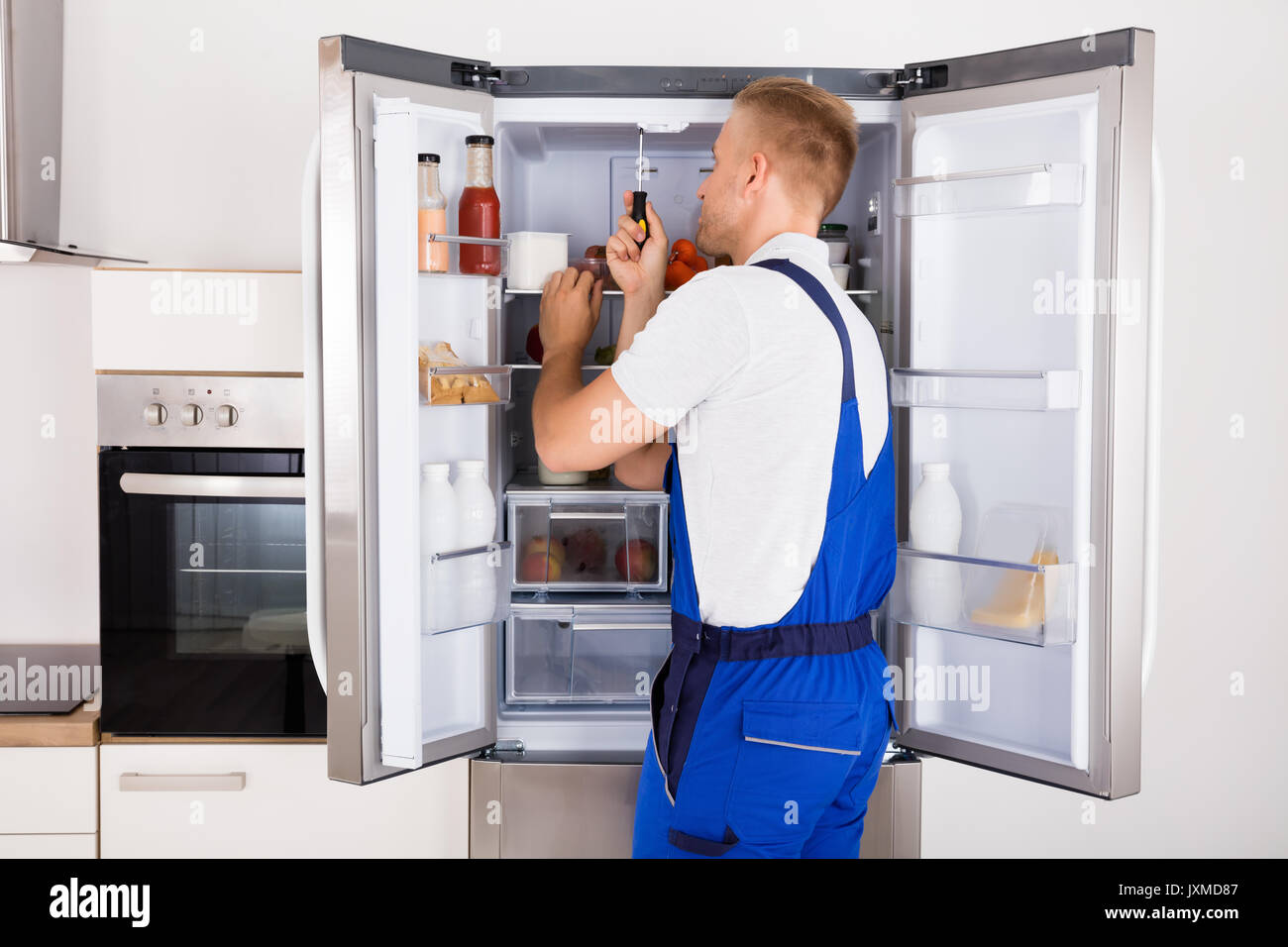 Tecnico di maschio rotto Riparazione Apparecchio frigorifero con il  cacciavite Foto stock - Alamy
