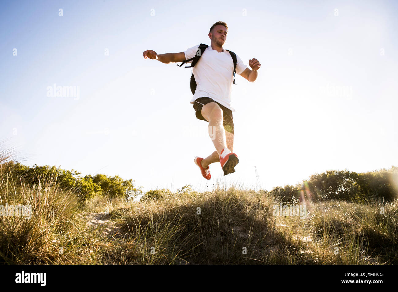 Giovane uomo formazione, saltando metà aria da dune di sabbia Foto Stock