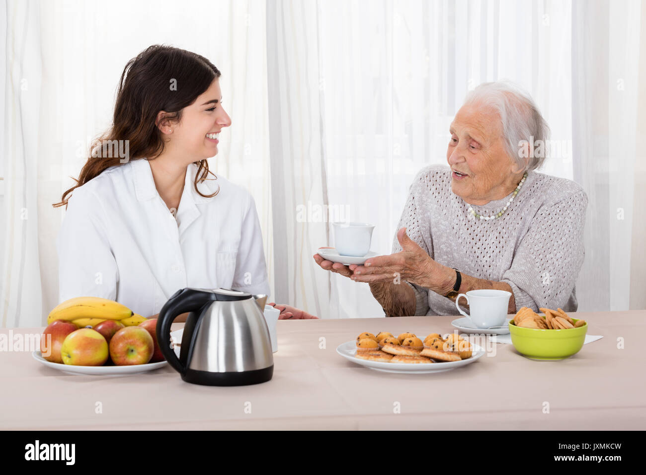 Il sambuco donna che offre caffè da infermiere pur avendo Tea Foto Stock