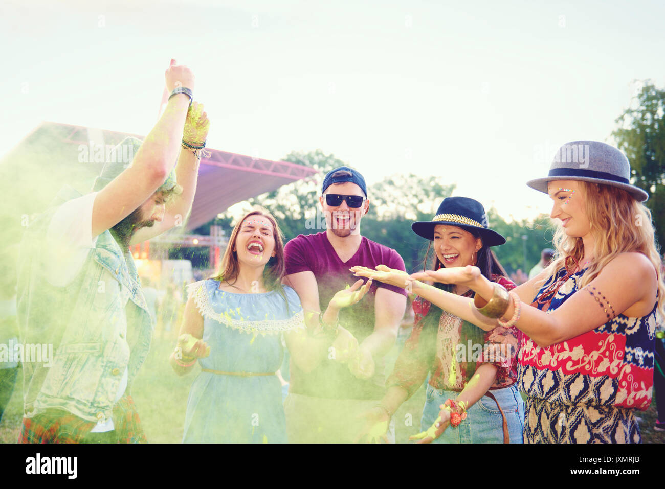 Giovani amici adulti gettando colorato polvere di gesso e ballare al festival Foto Stock