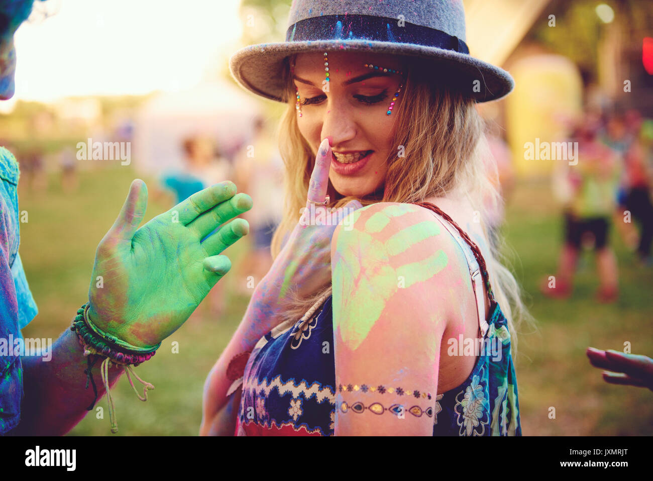 Giovane donna con handprint verde sulla spalla e il ragazzo conta la mano al festival Foto Stock