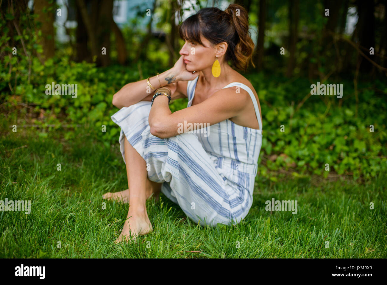 Metà donna adulta seduta zampe trasversale in giardino Foto Stock