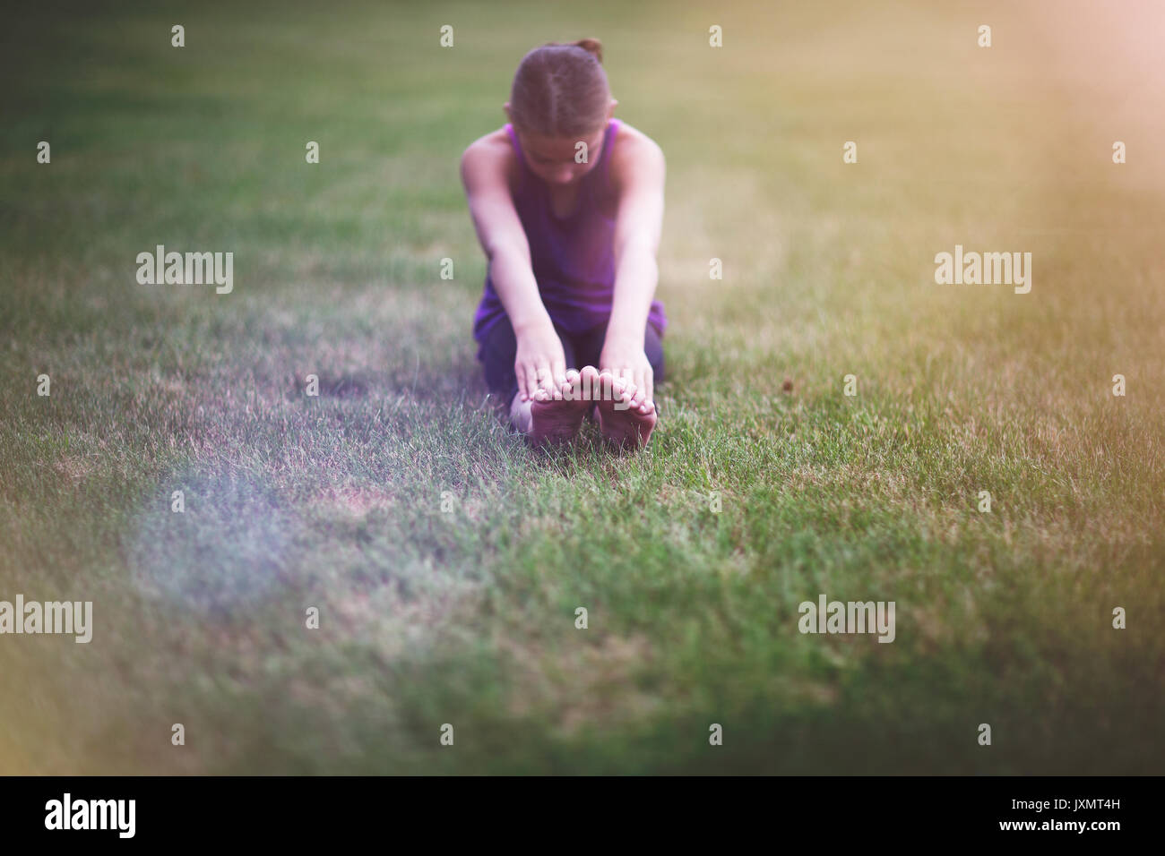 Ragazza stretching sull'erba Foto Stock