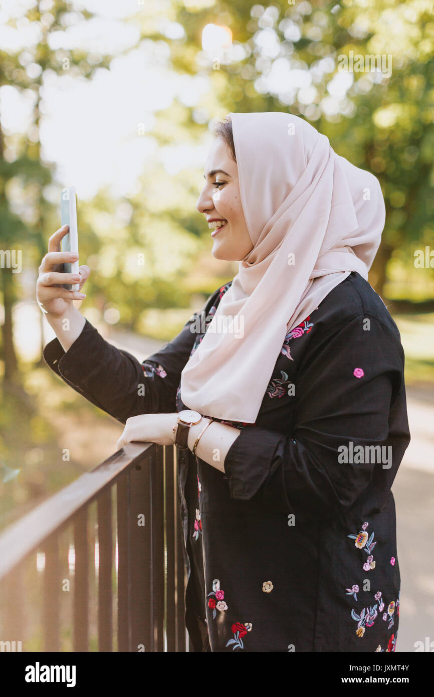 Giovane donna indossa hijab tenendo selfie sorridente Foto Stock