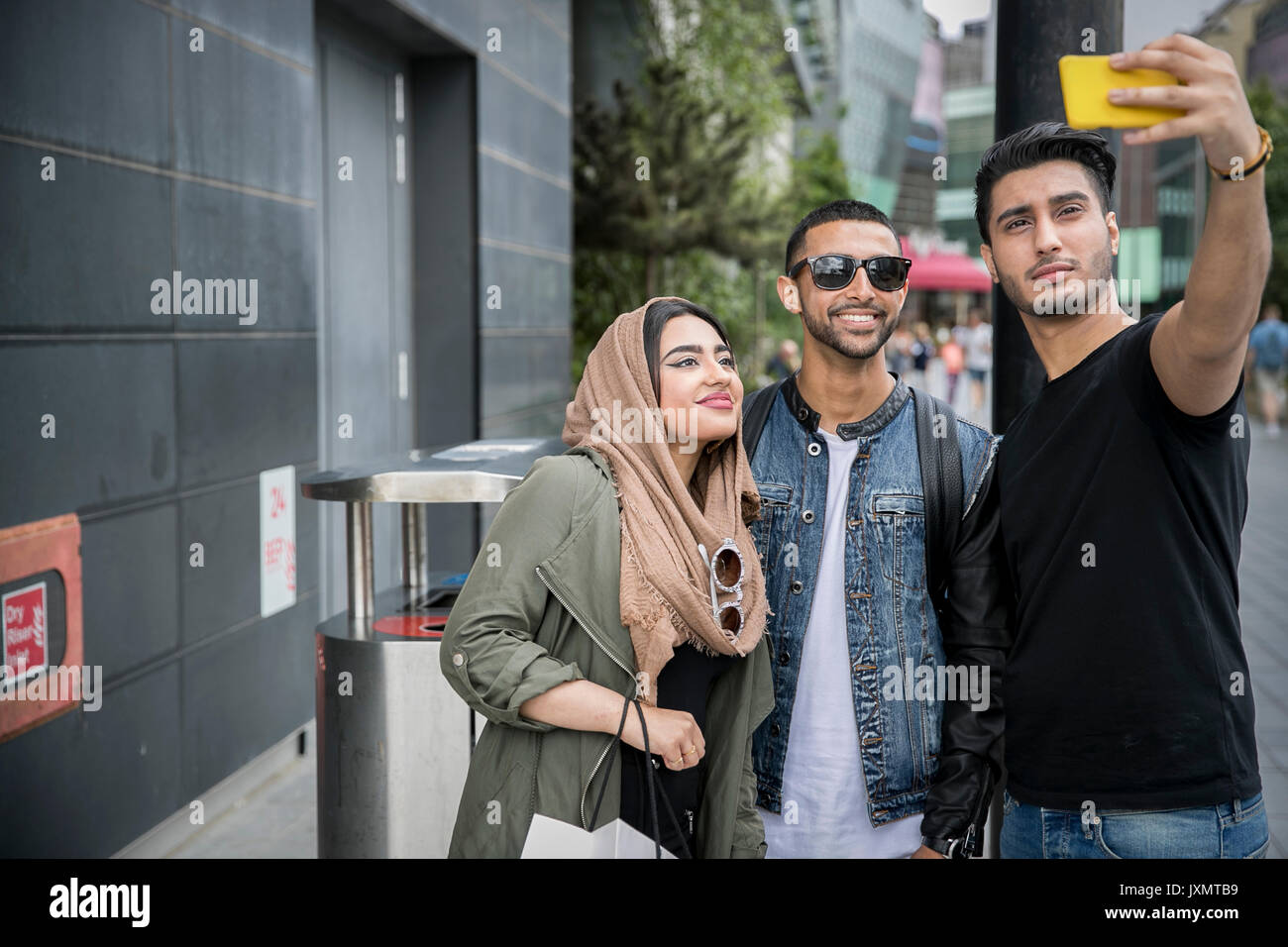 Tre amici in strada, tenendo selfie con lo smartphone Foto Stock