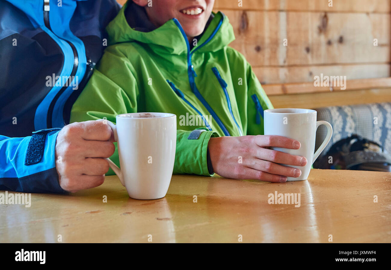 Padre e figlio prendendo pausa caffè in log cabin, Hintertux, Tirolo, Austria Foto Stock