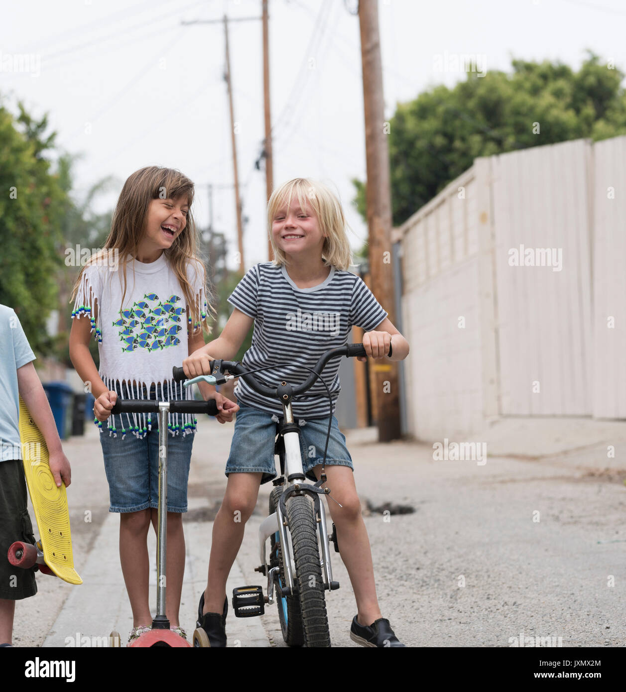 Ragazze e ragazzi in corsia con gli scooter, biciclette e skateboard Foto Stock