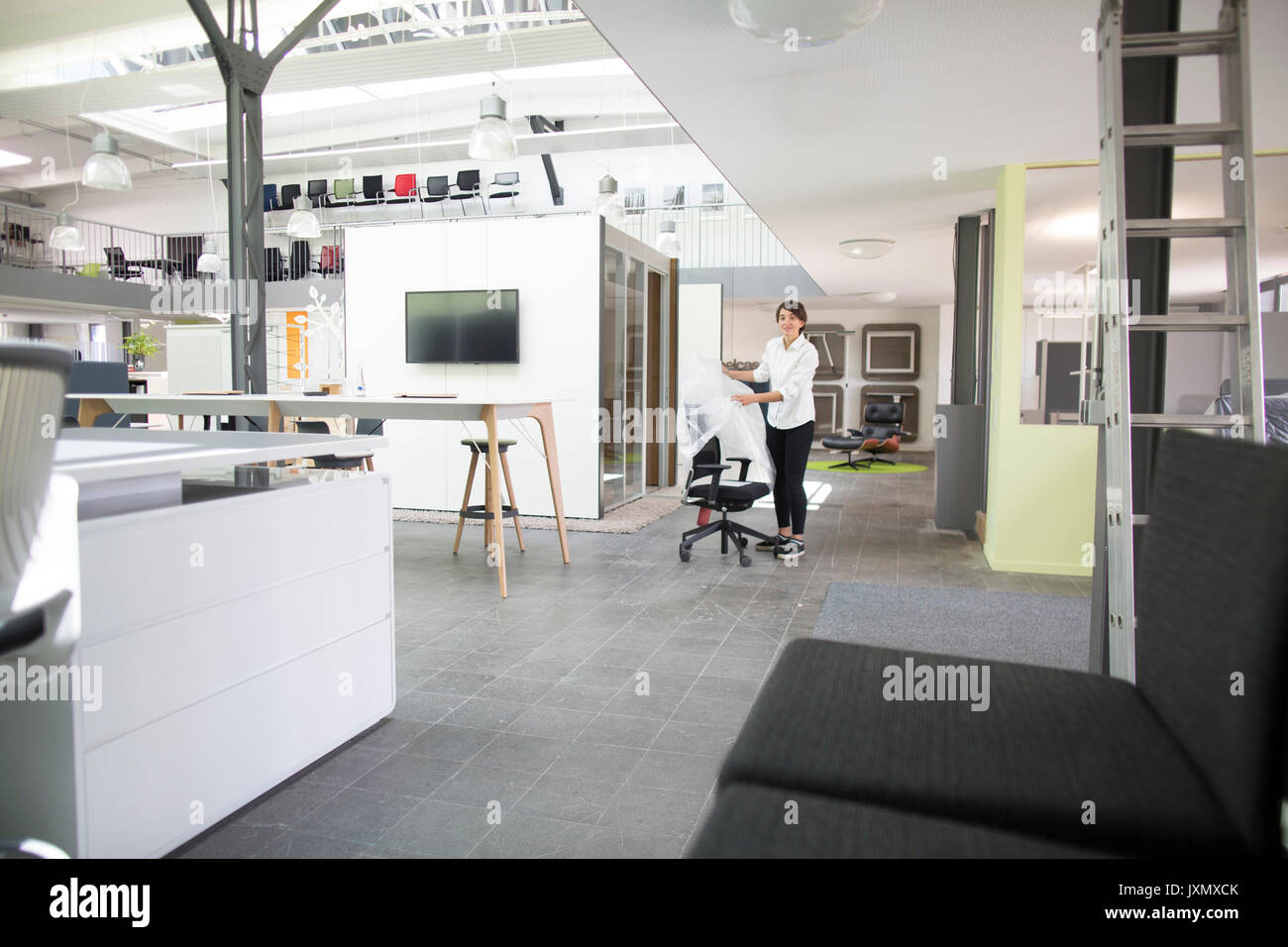 Giovani femmine sales manager di unwrapping sedia in office furniture store Foto Stock