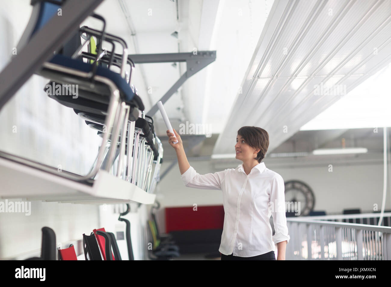 Giovani femmine sales manager rivolto a sedie in office furniture store Foto Stock