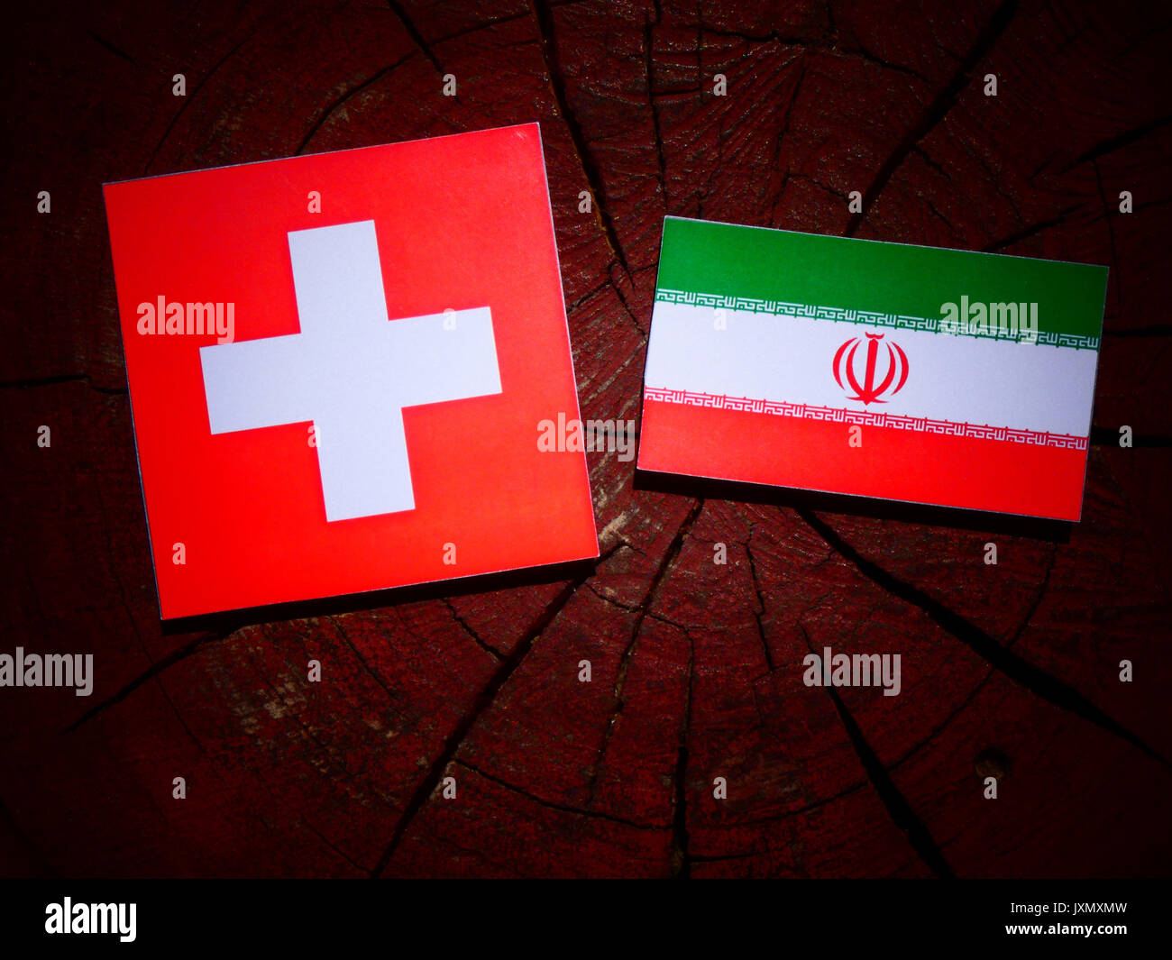 Bandiera svizzera con bandiera iraniana su un ceppo di albero isolato Foto Stock