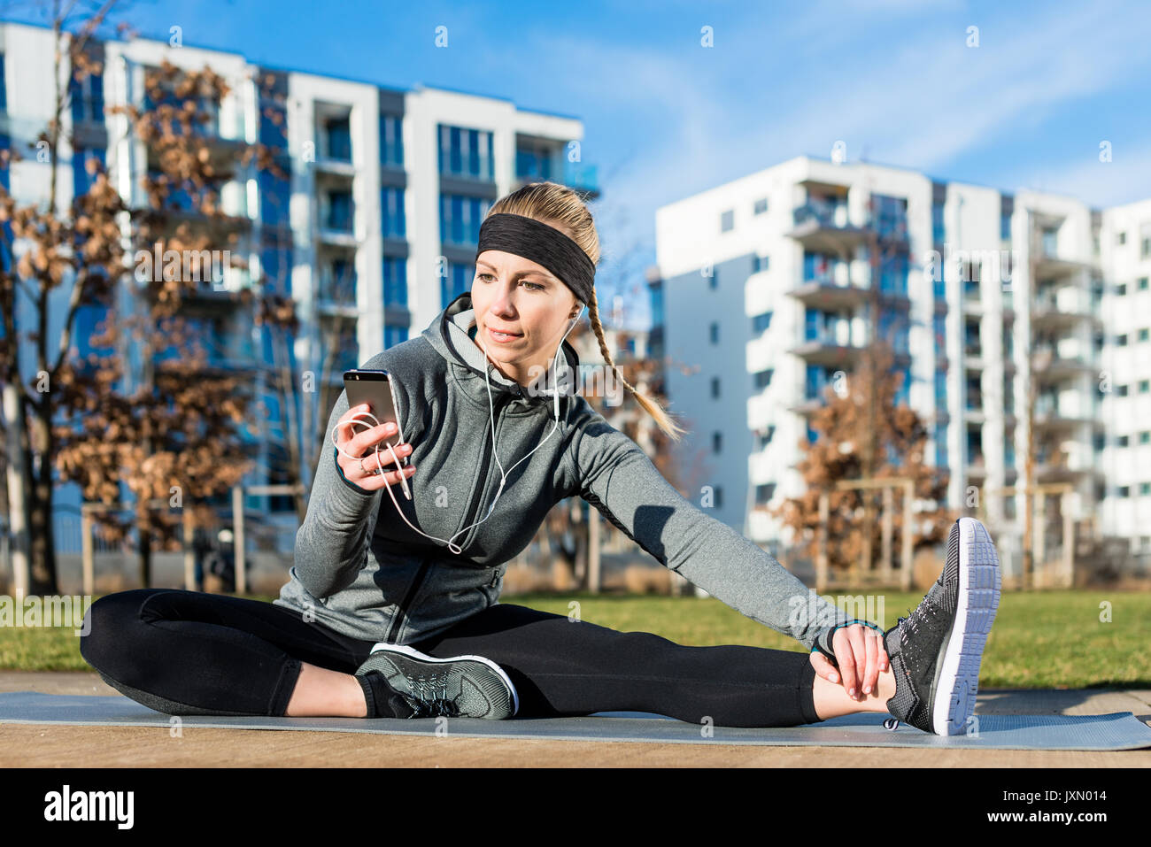 Attivo giovane donna controllando il suo telefono cellulare durante il lavoro all'aperto Foto Stock