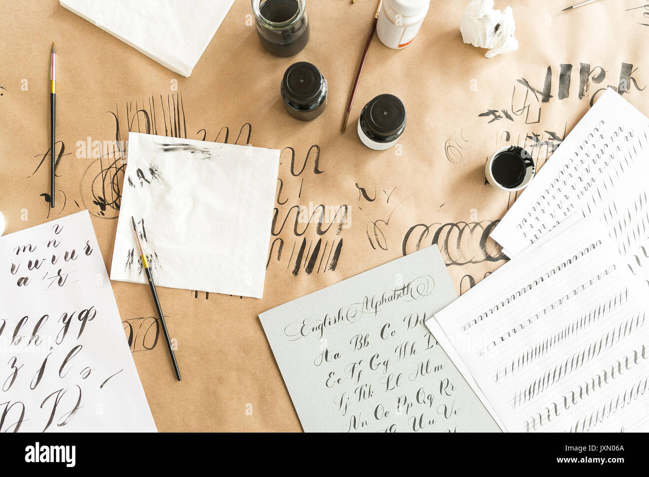 La calligrafia, design, creatività concetto. area di lavoro preparazione per la pratica in calligrafia con tutte le necessarie apparecchiature come inchiostro di due blac colore e bianco, spazzole, un sacco di carta e alcuni tovaglioli Foto Stock