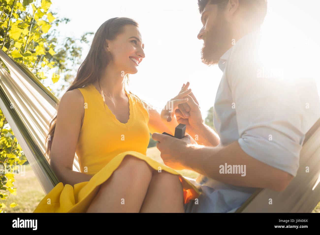 Uomo felice mettendo impegno anello al dito della ragazza sul Foto Stock