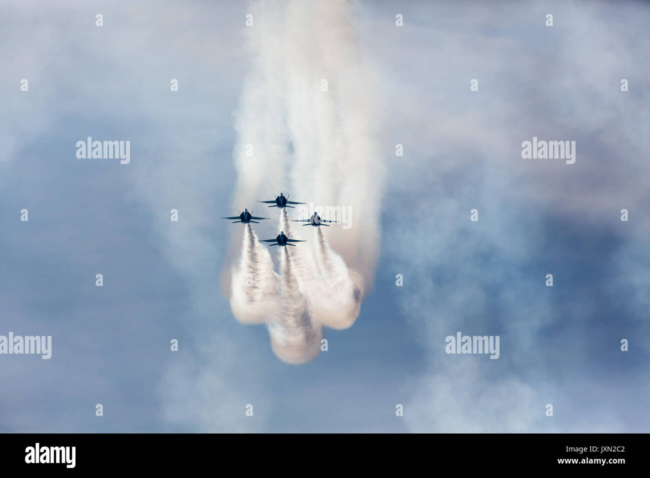 Gli aerei jet Blue Angels volano in formazione con piste di fumo contro un cielo blu Foto Stock