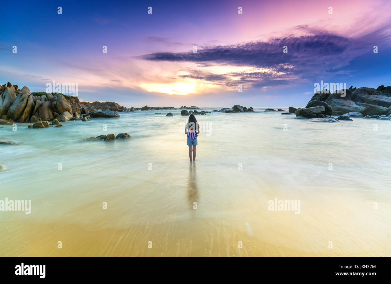 Giovane donna da soli in piedi da solo sulla roccia vulcanica guardare sull orizzonte immensità di alba come aspirazioni, sperando che le cose buone per il futuro in Mui ne Foto Stock