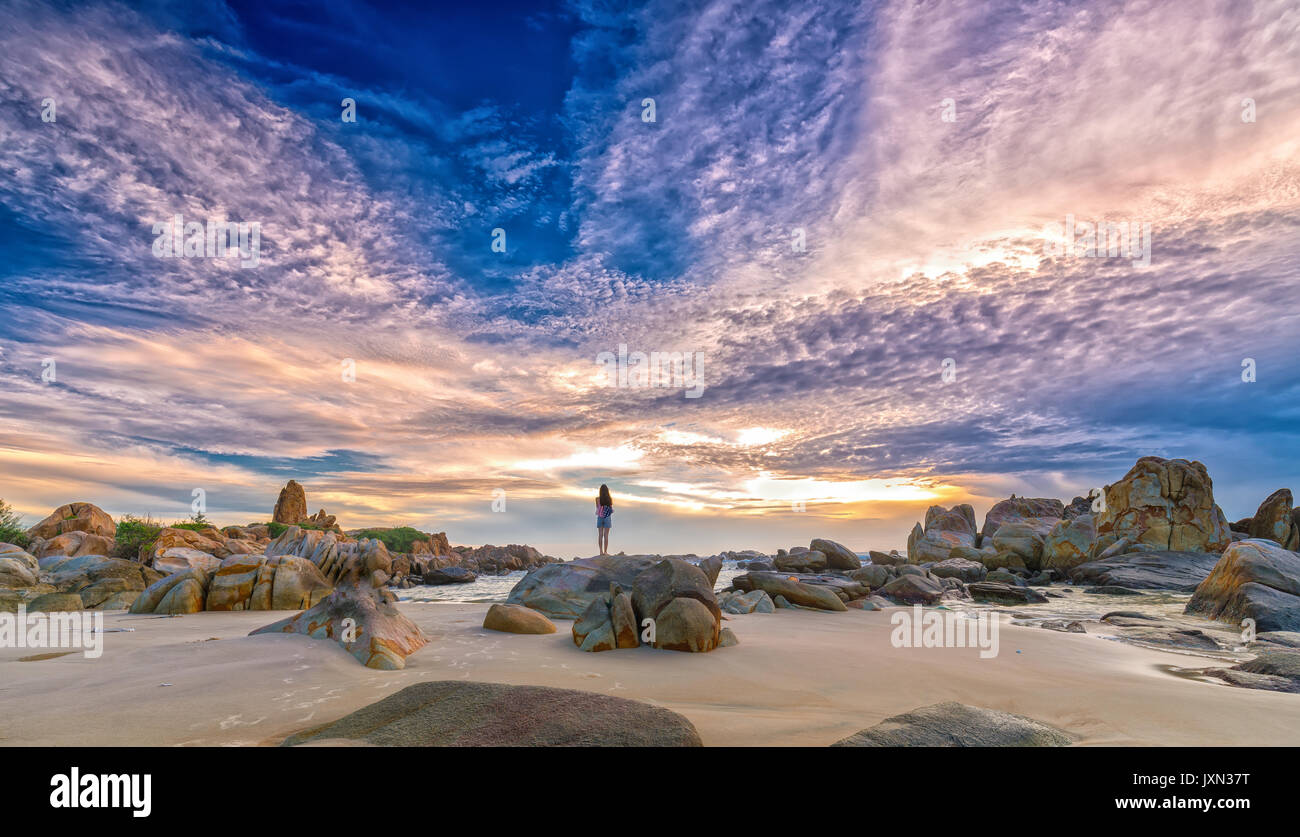 Giovane donna da soli in piedi da solo sulla roccia vulcanica guardare sull orizzonte immensità di alba come aspirazioni, sperando che le cose buone per il futuro in Mui ne Foto Stock