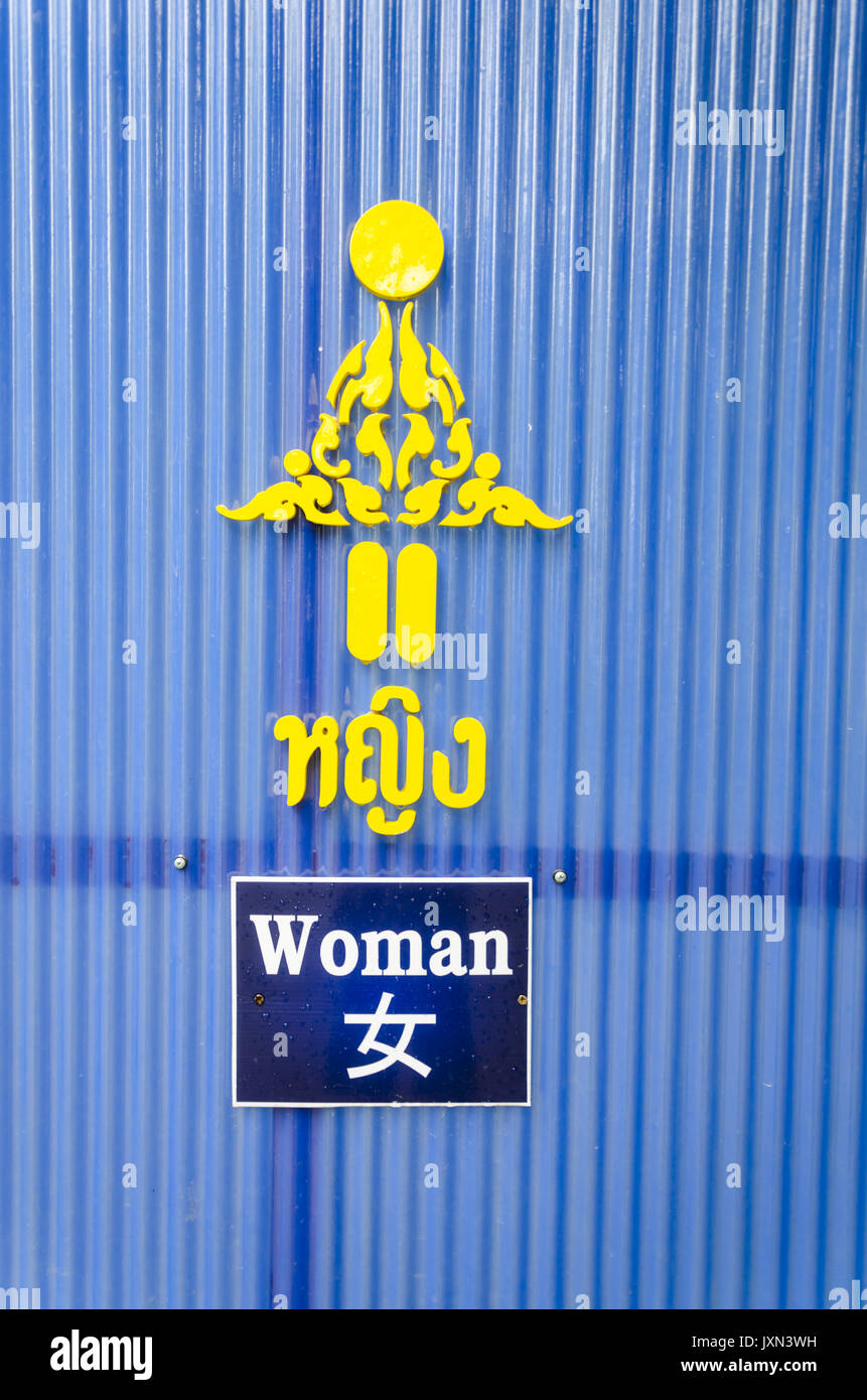 Wat Rong Sear Tean, fantasia donna restroom sign in Thai, inglese e cinese con emblema dorato al Tempio Azzurro, Chiang Rai, Thailandia Foto Stock