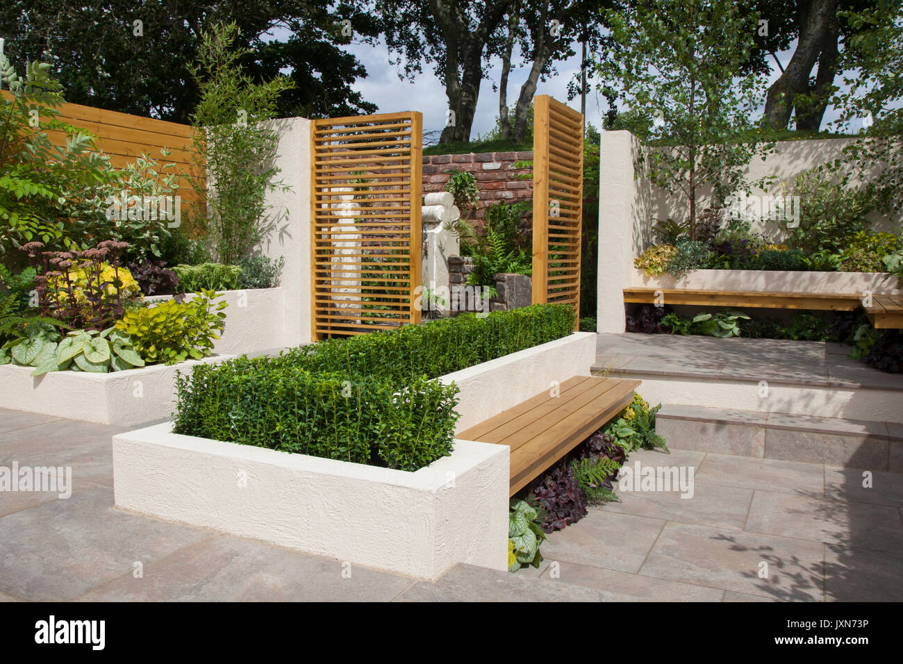 Un giardino espositivo con cancelli in legno con feritoie, panchine e copertura a clip a Southport, Merseyside, Regno Unito, nel 2017. Dispone di una moderna e contemporanea sala giardino con cortile, bordi rialzati, aree patio e acqua. Nell'ultimo giorno di preparazione del Flower Show, espositori, designer di giardini e artisti floreali aggiungono i tocchi finali alle mostre destinate a stupire i visitatori di questo famoso evento annuale. Foto Stock