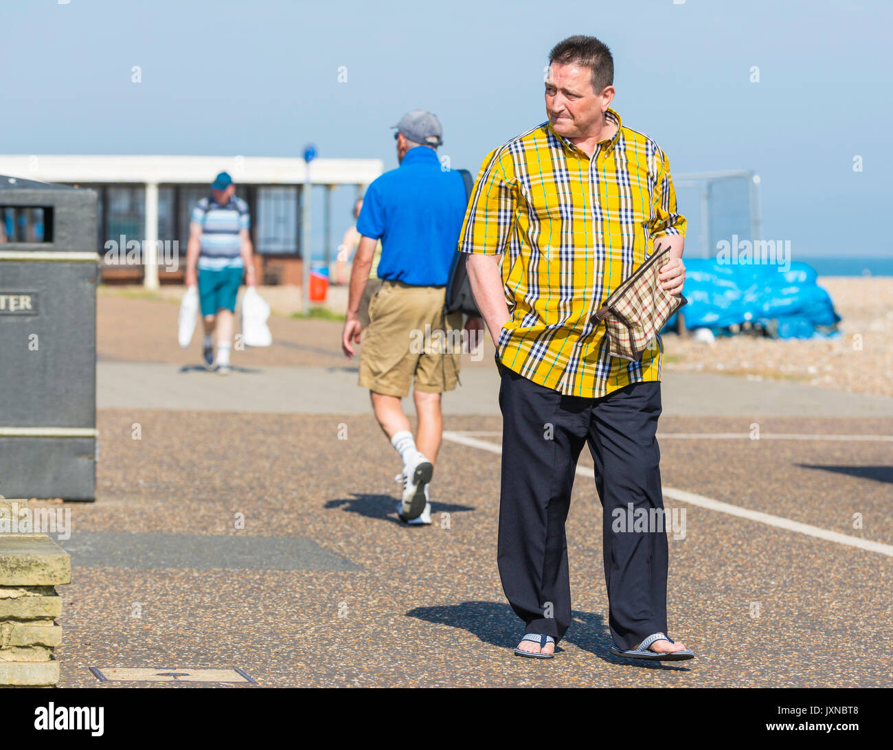 Casualmente vestito uomo di mezza età a piedi lungo un sentiero in estate indossa sandali. Foto Stock