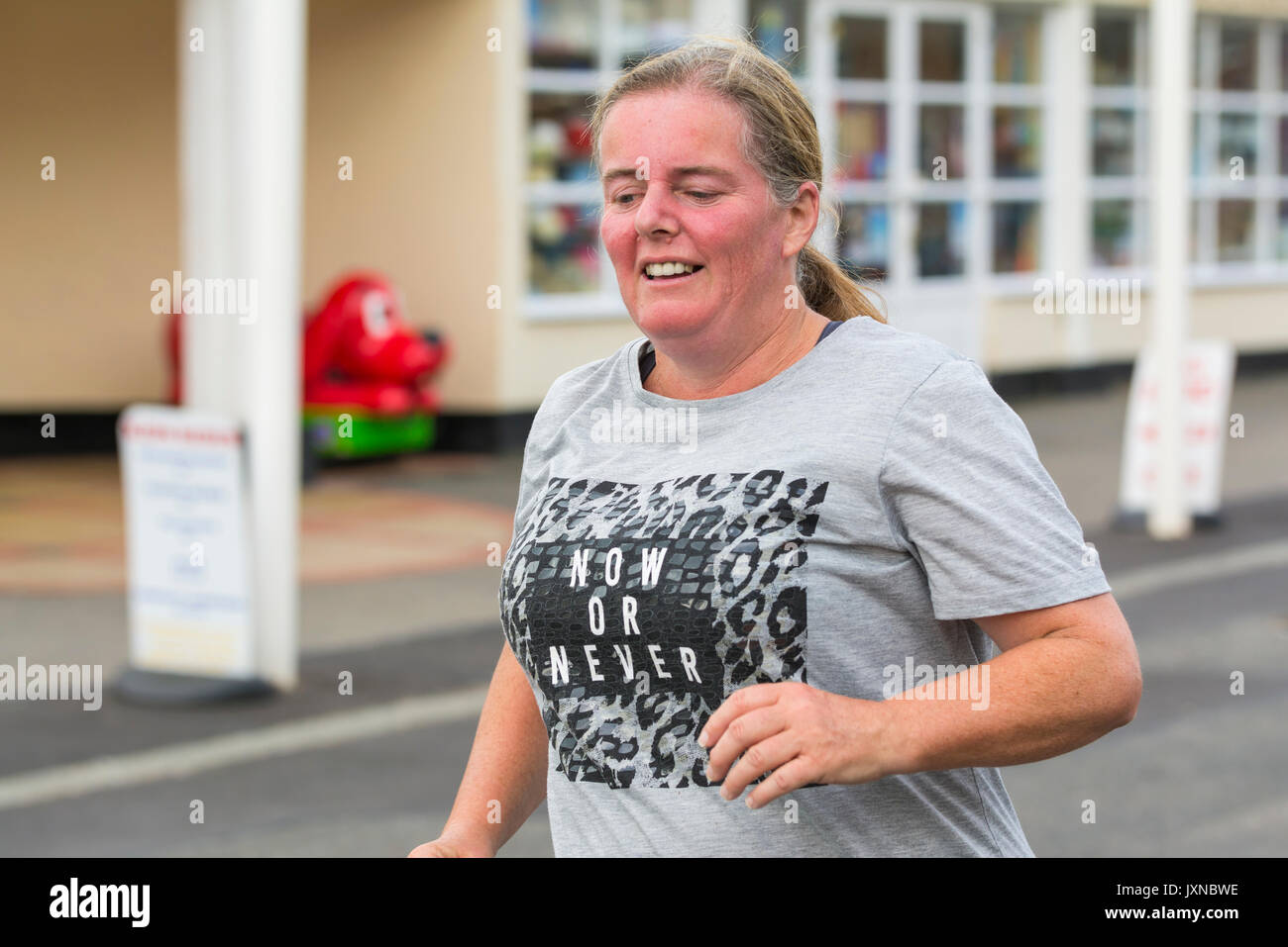 Di mezza età Donna sovrappeso in esecuzione come parte del piano per perdere peso e per ottenere la misura, a Worthing vitalità Parkrun evento. Foto Stock