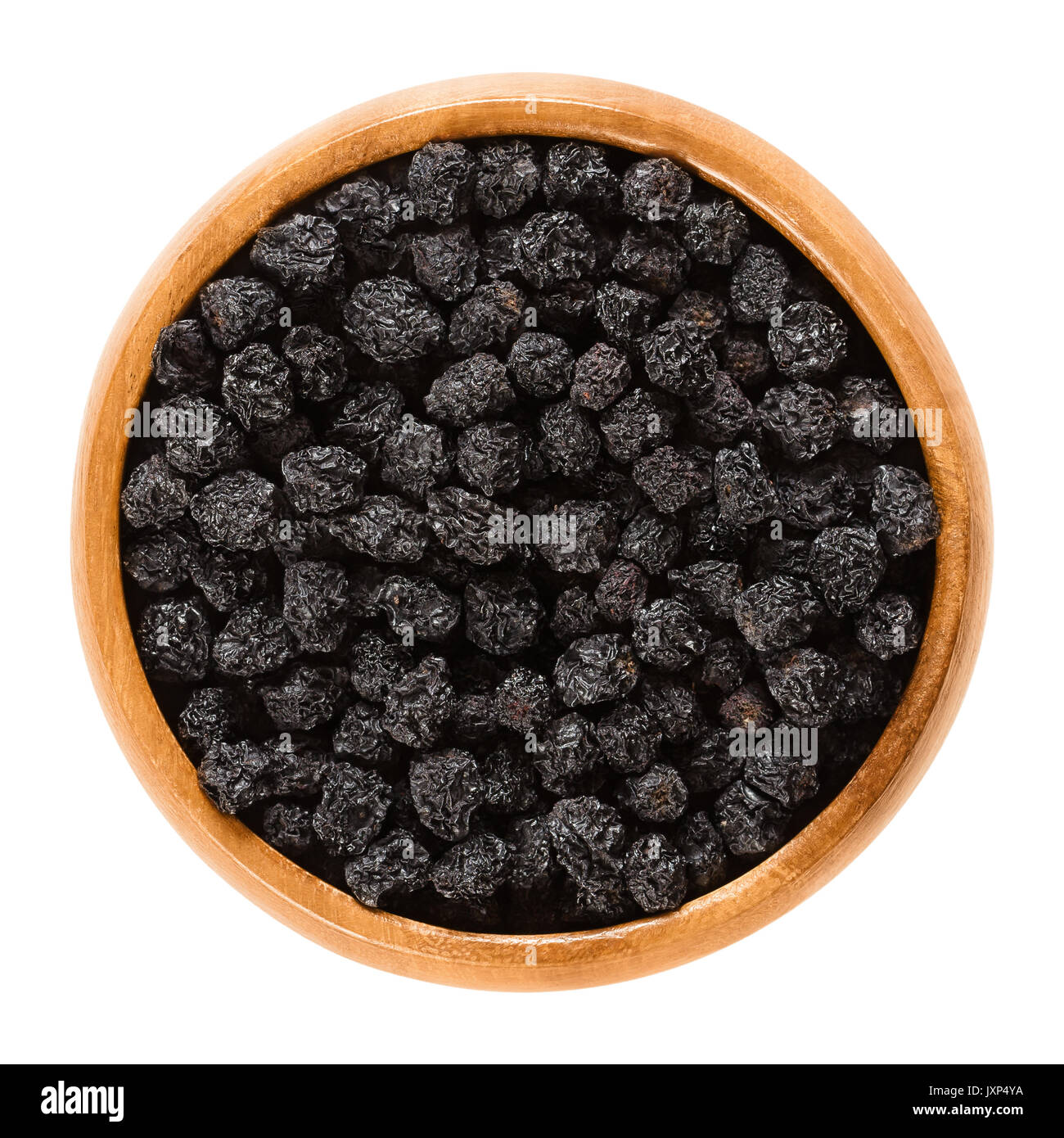 Bacche di Aronia nella ciotola di legno. Essiccato mature chokeberries nero, Aronia melanocarpa. I frutti sono utilizzati come aromatizzante o un colorante. Macro foto di cibo. Foto Stock