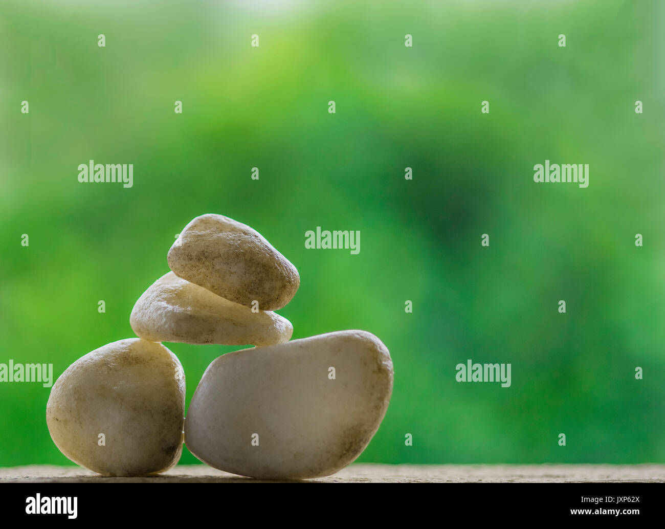 Equilibrare le rocce e ciottoli con un albero verde come sfondo Foto Stock
