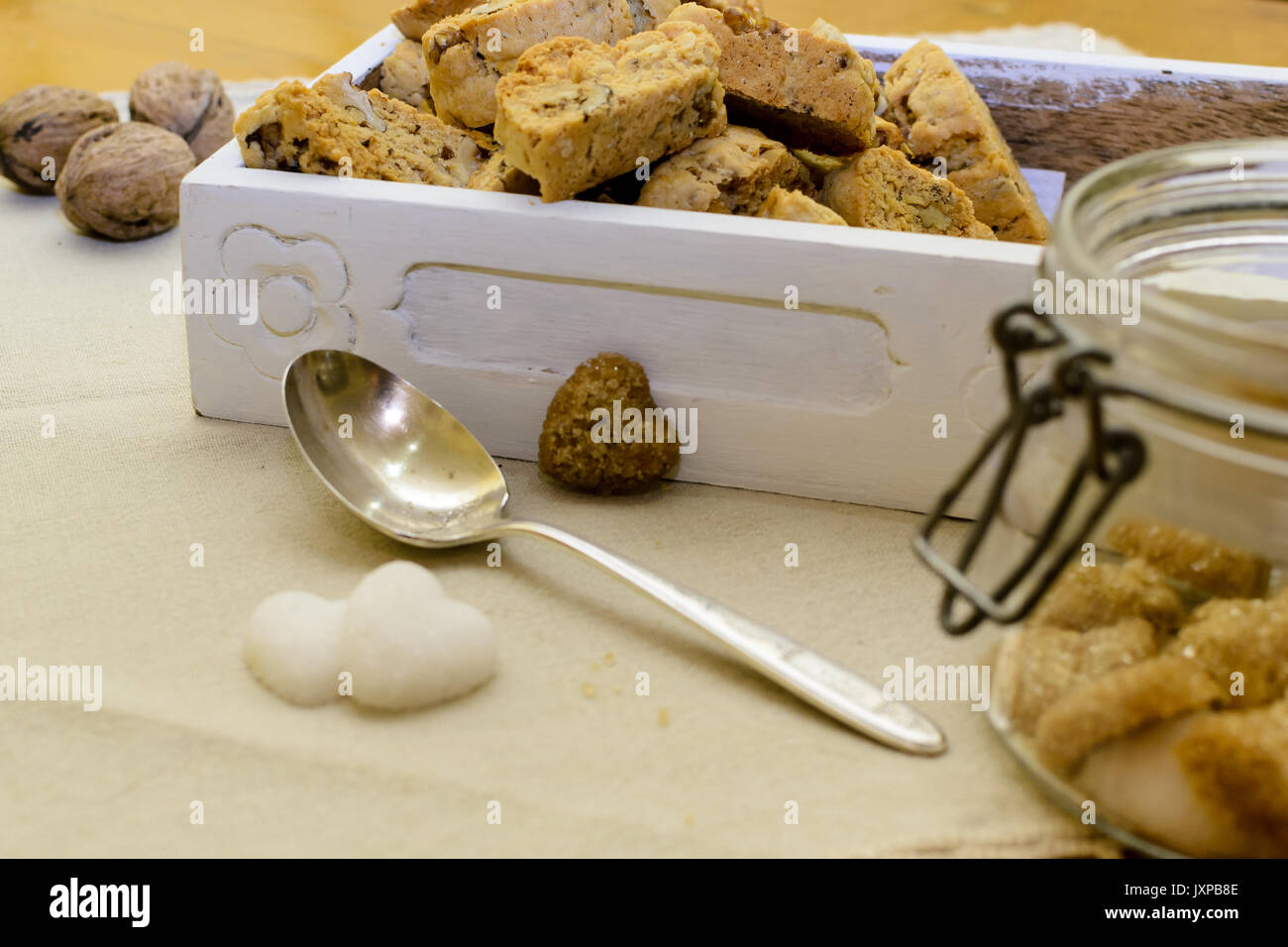Tozzetti italiano in un bianco scatola di legno con a forma di cuore i cubetti di zucchero e un cucchiaio d'argento. Vista laterale. Formato orizzontale. Foto Stock