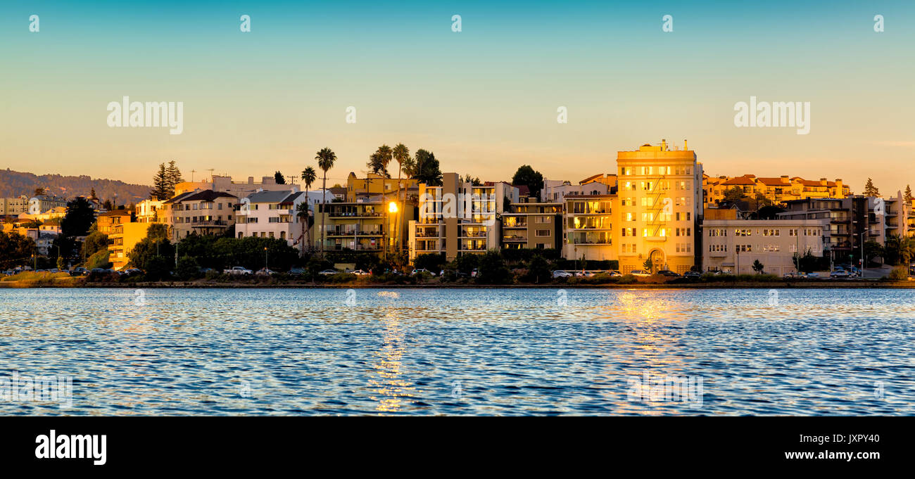 Oakland, la California Lago Merritt edifici sul lungomare illuminato di golden al tramonto. Vista dall'acqua. Foto Stock