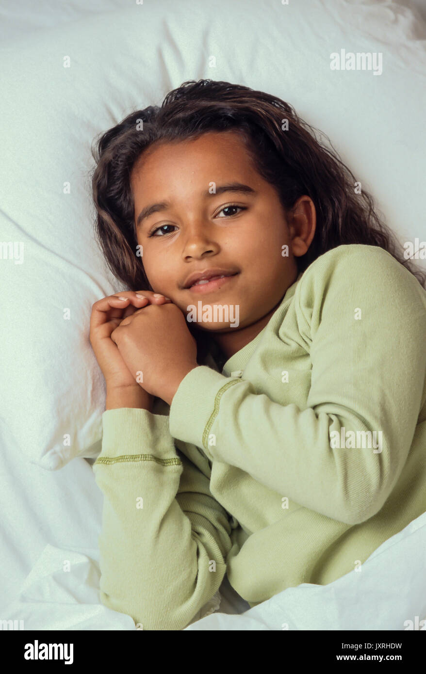 Andare a dormire per la giovane ragazza 7-10 anni in letto pronto a pregare e di andare a dormire African American/Caucasian Foto Stock