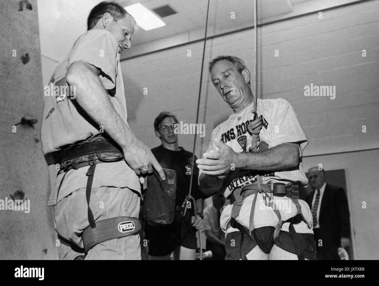 Michael Rubens Bloomberg, colpo di Candid, Bloomberg si sta calpestando le mani e si è agganciato a un'imbracatura di sicurezza in preparazione all'arrampicata su una parete da arrampicata interna, circa 47 anni, 1997. Foto Stock