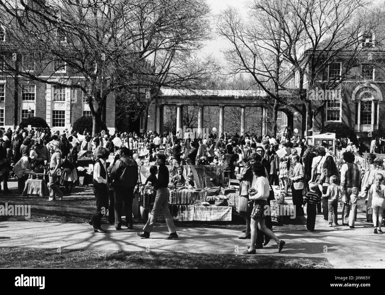 Studenti che camminano in gruppo alla Spring Fair, un carnevale primaverile, all'aperto, tende da venditori e una grande folla sullo sfondo, alla Johns Hopkins University, 1972. Foto Stock