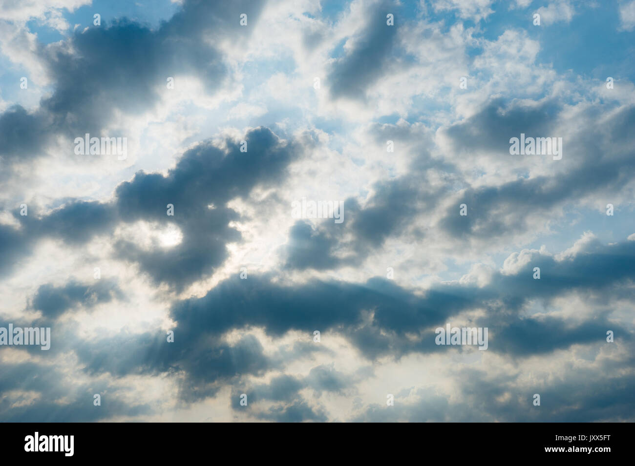 Sole che splende attraverso le nuvole in cielo blu, sullo sfondo della natura Foto Stock