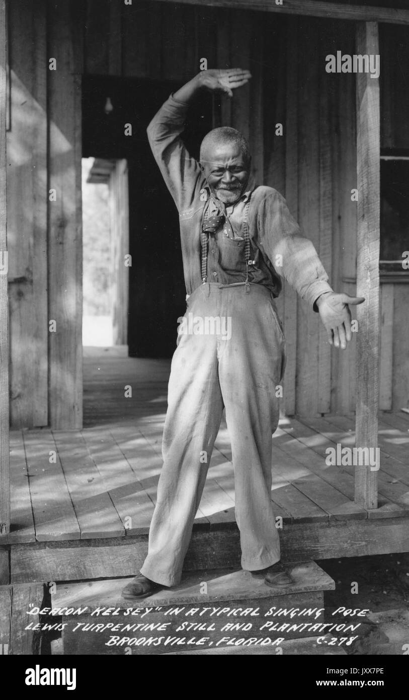 Ritratto a lunghezza intera di un uomo afroamericano maturo che fa gesti elaborati a mano sulla piantagione di Lewis, sui gradini di un edificio, 1940. Foto Stock