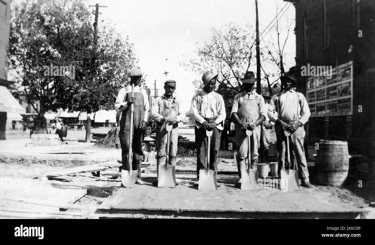 Foto a lunghezza intera di quattro ragazzi afro-americani, che si pongono allo stesso modo con pale davanti alle gambe, all'aperto; Libano, Pennsylvania, 1920. Foto Stock