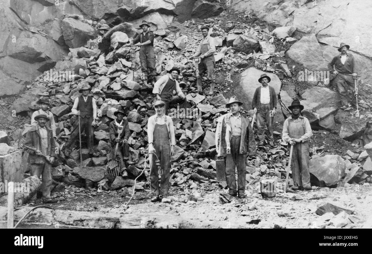 Americano africano bianco e i minatori sono sparsi su una collina di rocce di grandi dimensioni, sono tutte in posa per la foto, 1920. Foto Stock