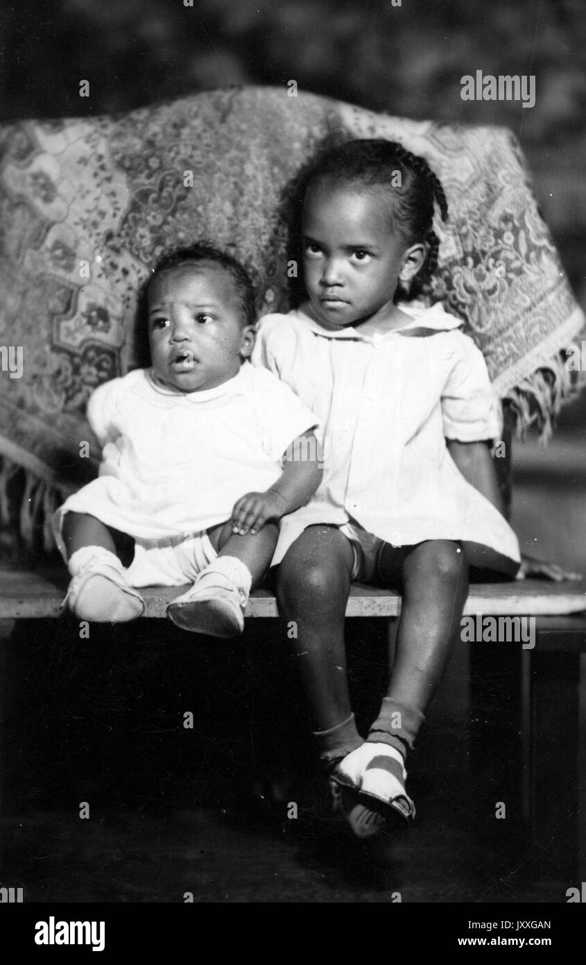 Ritratto completo, due bambini afroamericani--un bambino, e un'altra ragazza più anziana, seduto, guardando in direzioni diverse, espressioni facciali neutrali, 1920. Foto Stock
