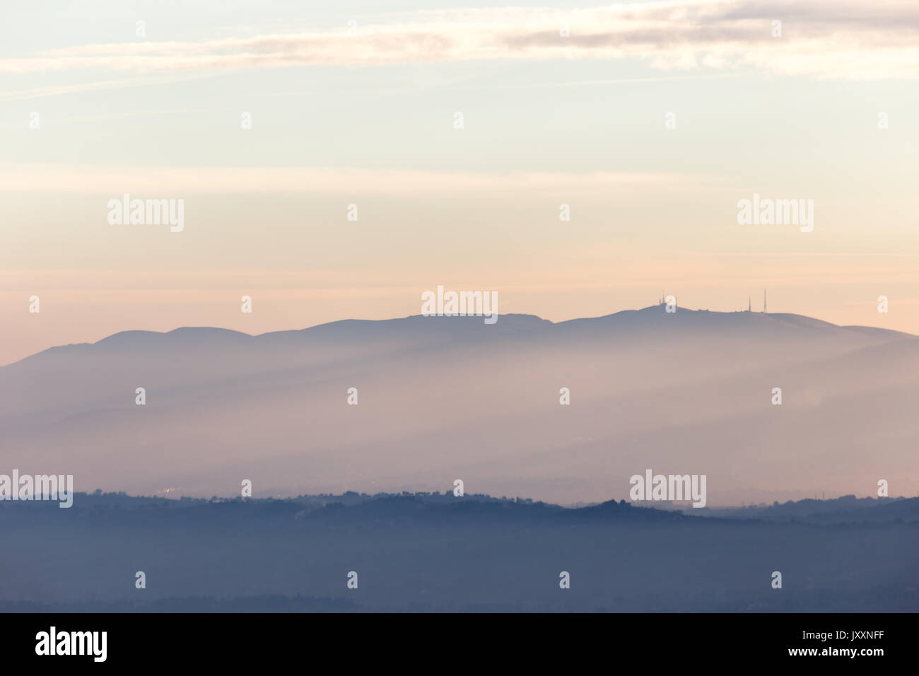 Raggi di sole che esce dietro alcune montagne e colline al tramonto Foto Stock