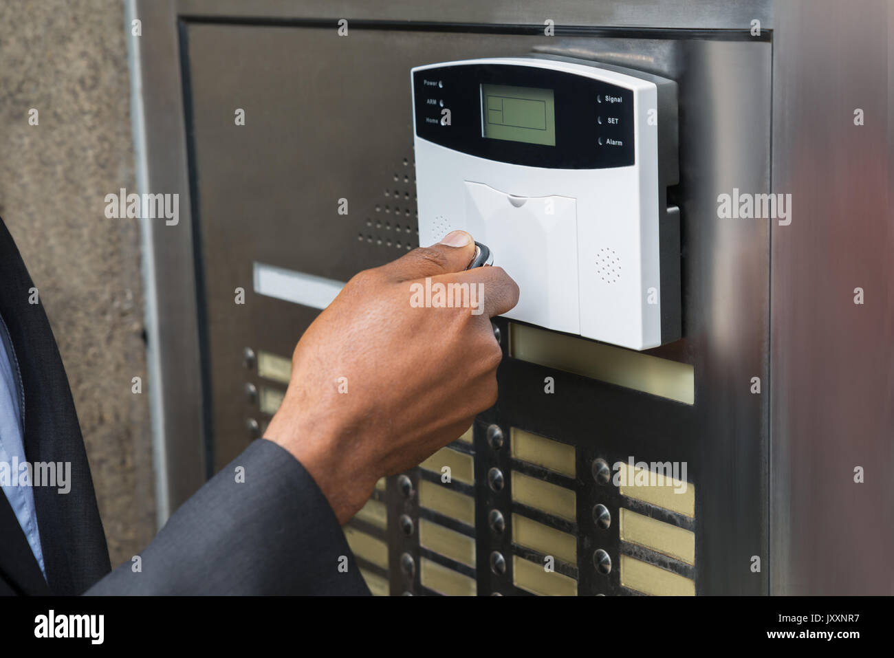 Close-up di commercianti la mano utilizzando il telecomando per il funzionamento di porte con sistema di sicurezza Foto Stock