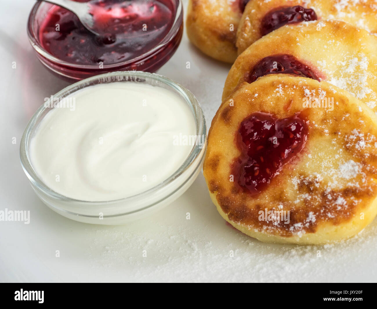 Frittelle di cagliata e panna acida su un tavolo Foto Stock