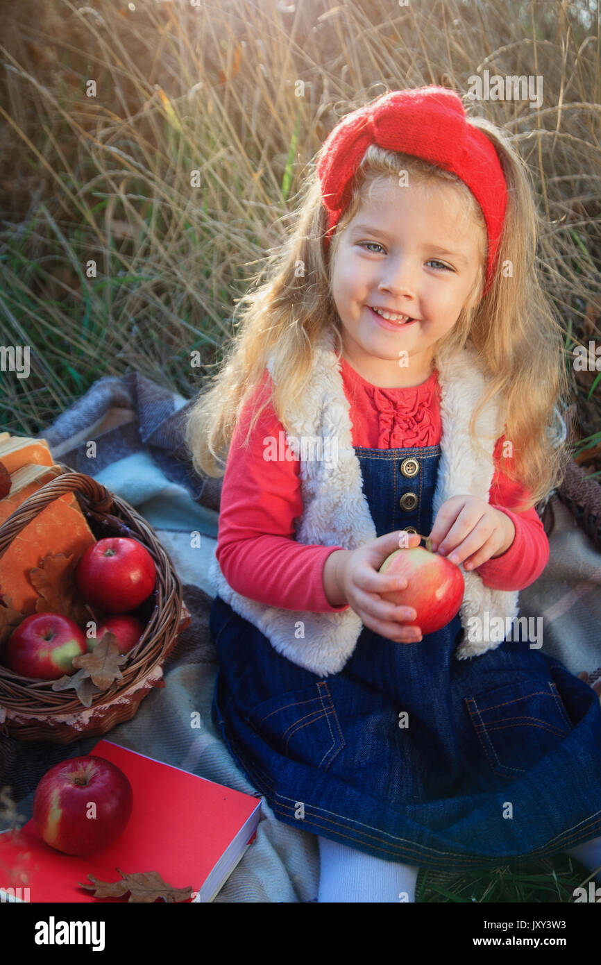 Bambina sulla natura con una cesta di frutta e libri. Foto Stock