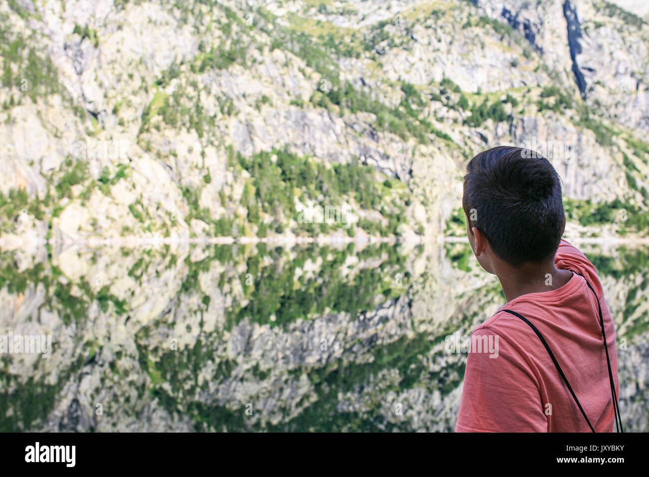 Ragazzo che guarda al lago e monti foto con la riflessione Foto Stock