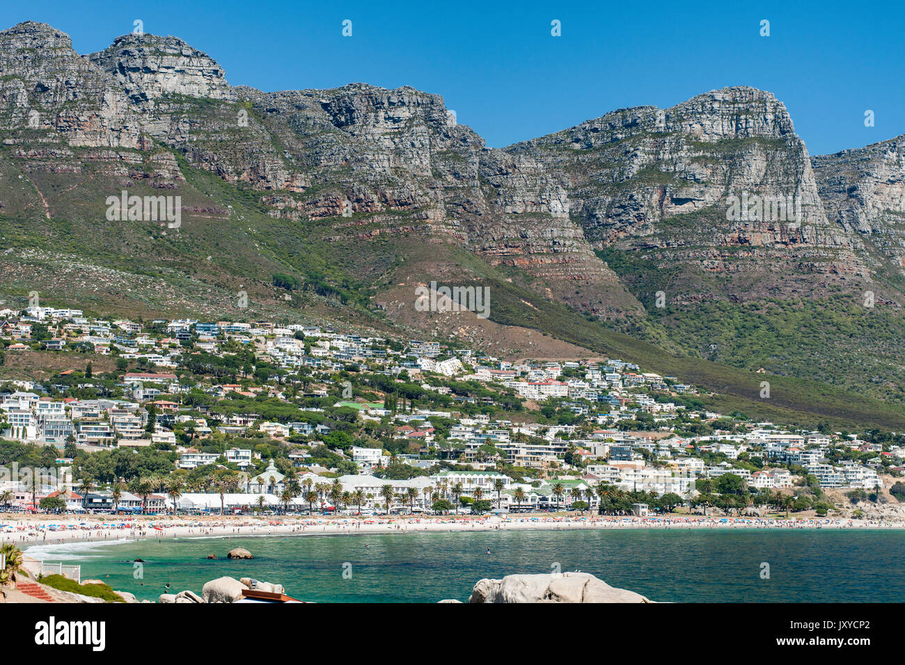 La spiaggia di Camps Bay e di case e alcuni dei picchi dei dodici apostoli montagne di Città del Capo in Sud Africa. Foto Stock